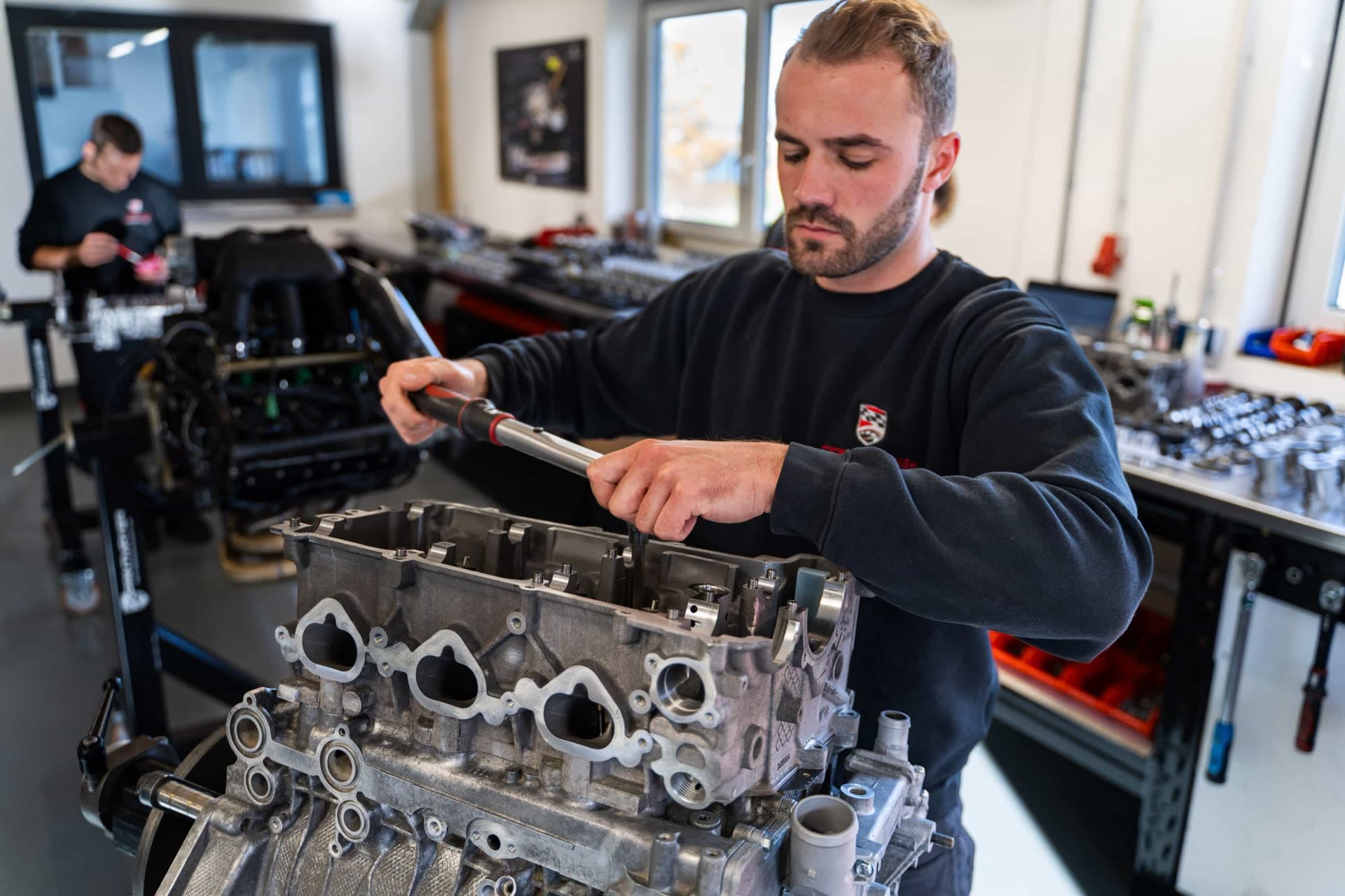 Mechaniker montiert einen Motorblock in einer Werkstatt.