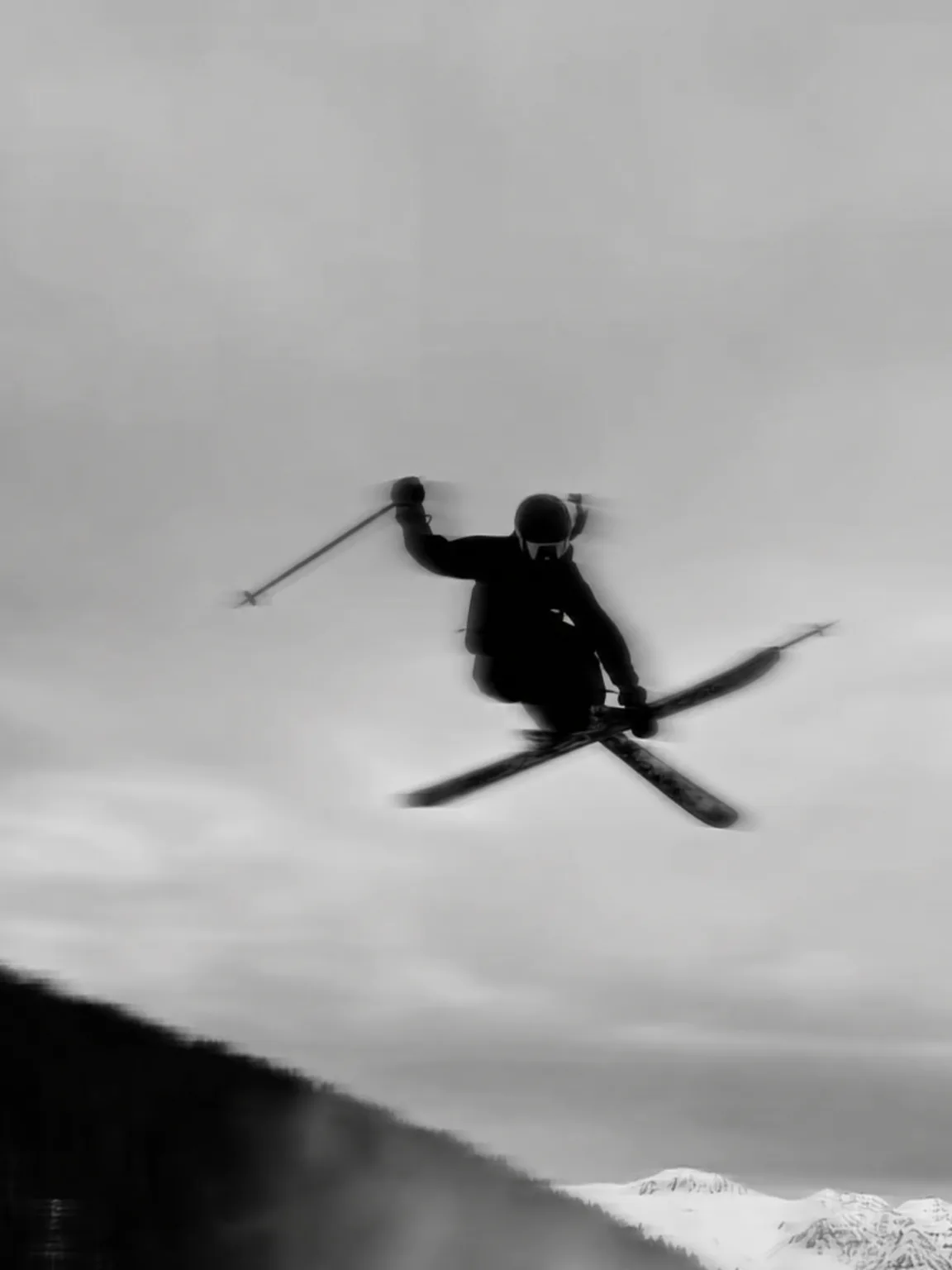 Skisprung mit gekreuzten Skiern gegen den Himmel, in Schwarzweiß