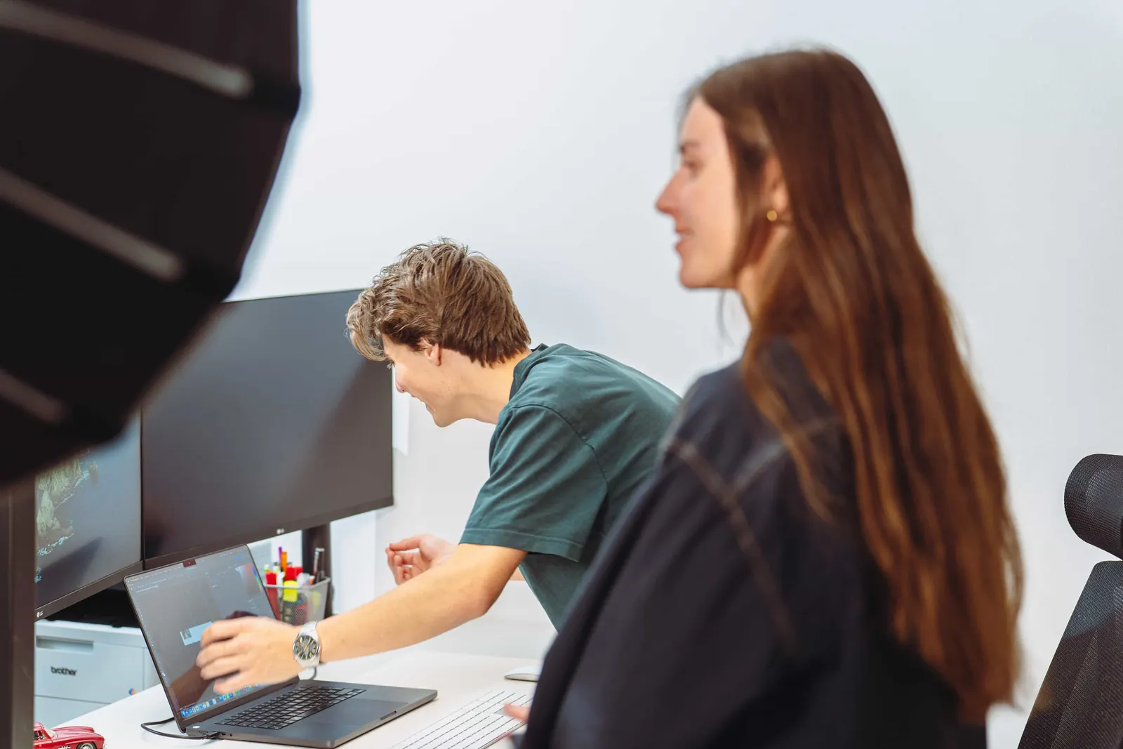 Zwei Mitarbeitende von Invisions besprechen ein Layout am Laptop im Innsbrucker Büro.